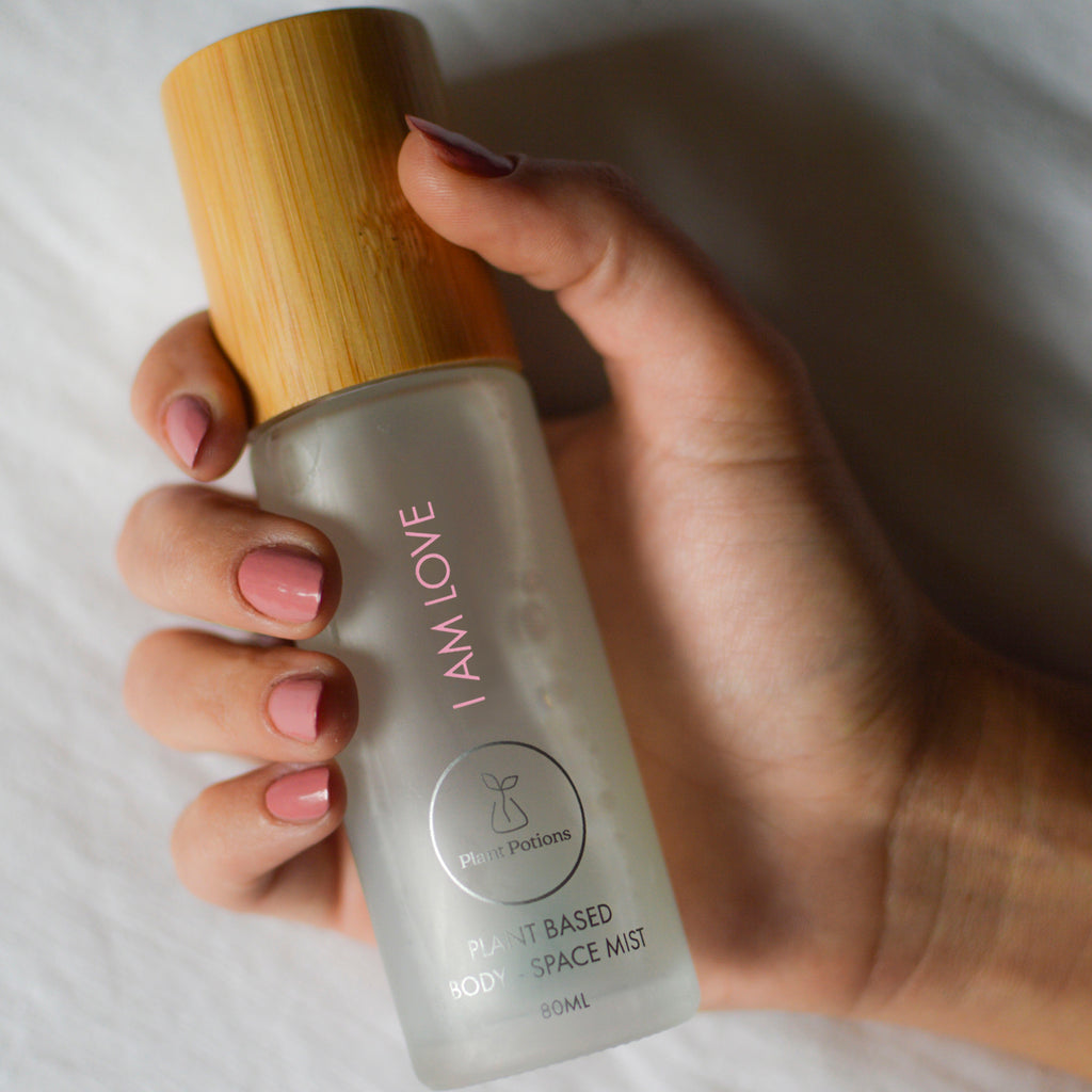 love body mist held in a womans hand with pink manicured nails
