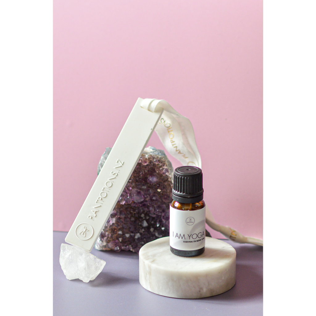 essential oil bottle with stick diffuser and an amethyst crystal