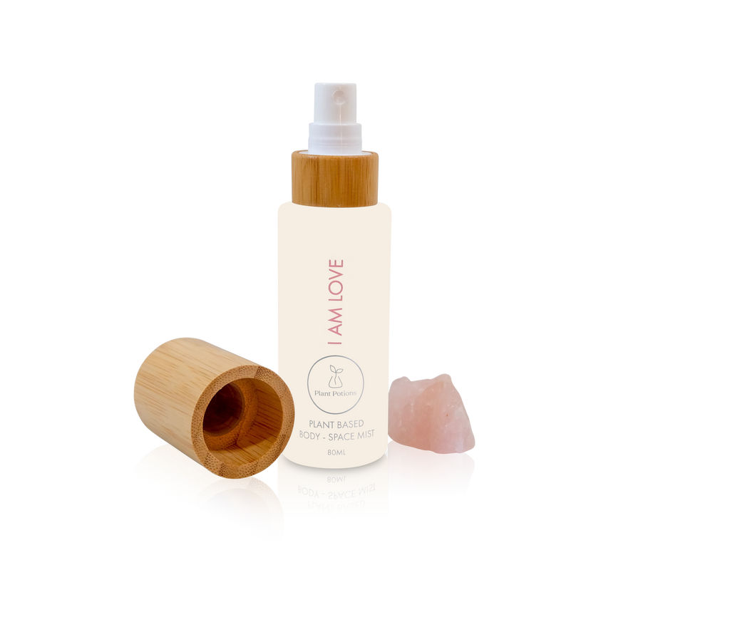 rose body mist in a glass bottle woth bamboo lid to the side and rose quartz crystals